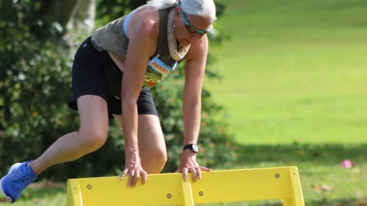 Woman jumping over yellow barrier in park