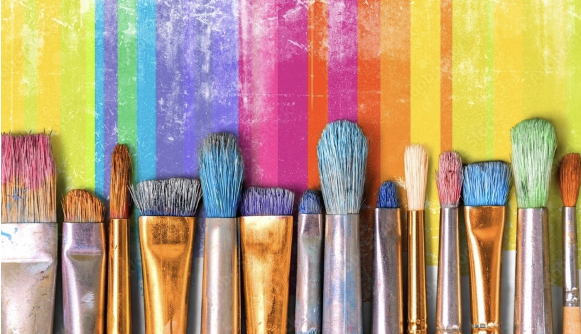 Colorful paintbrushes on vibrant rainbow background