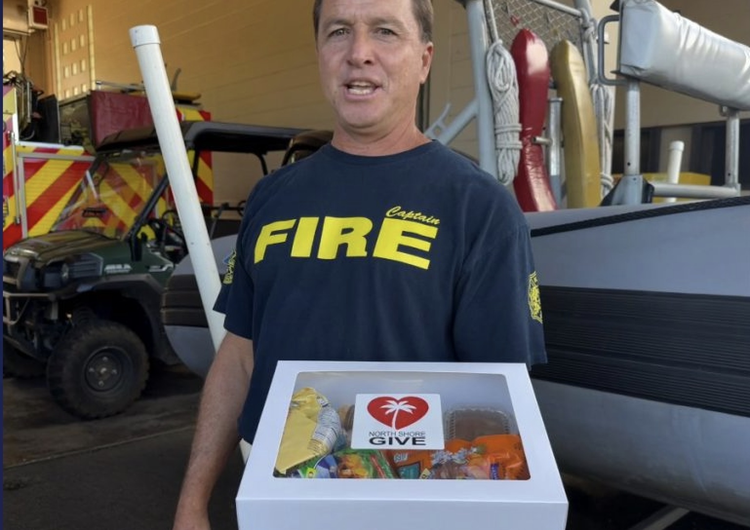 Firefighter holding North Shore Give gift box