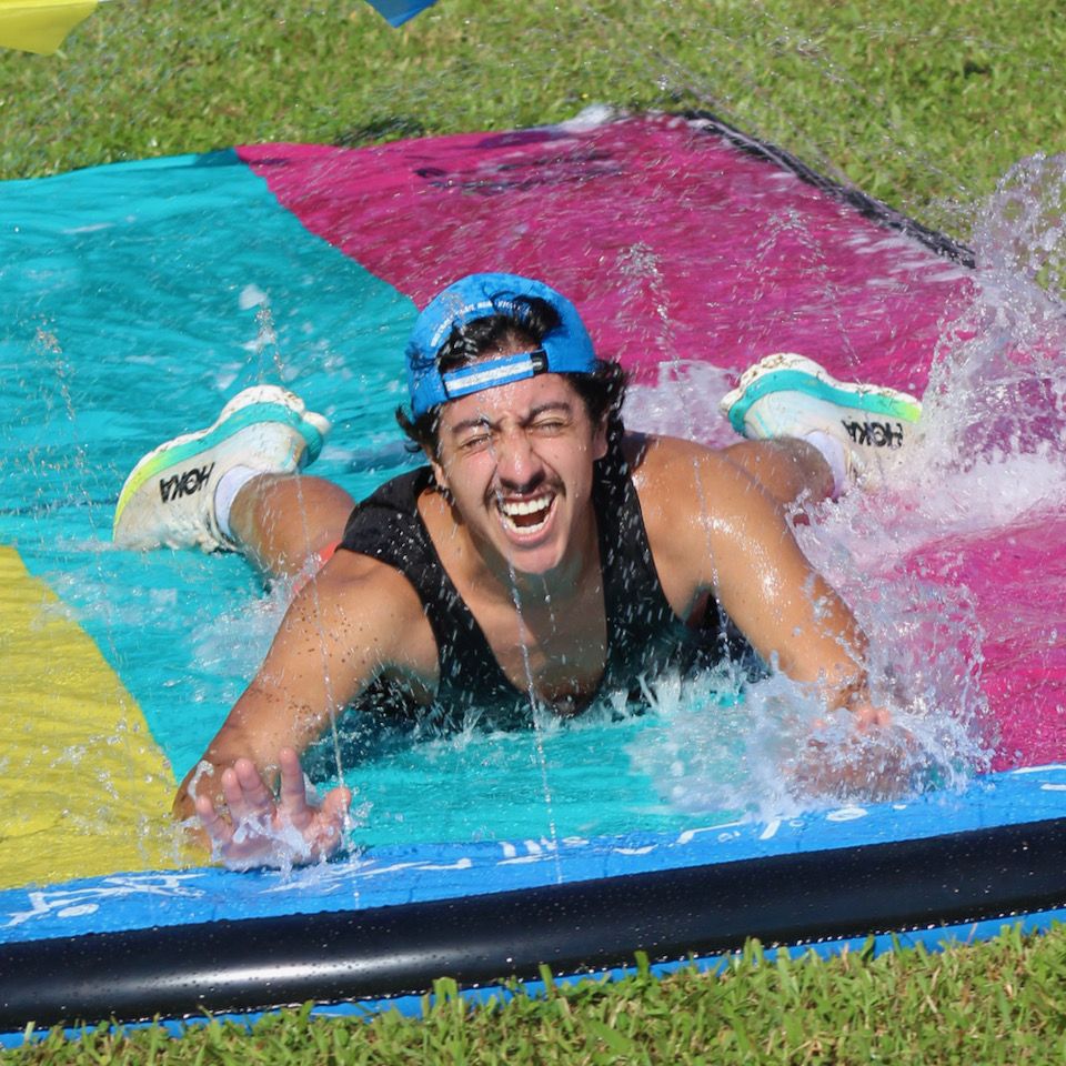 Man sliding belly-first on colorful inflatable water slide