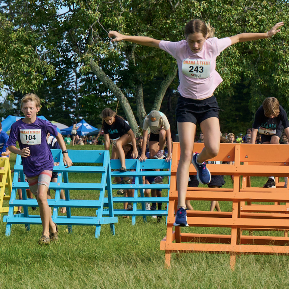 Children leap over colorful hurdles during outdoor fitness race